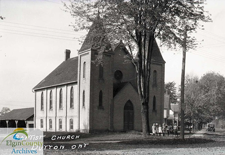Black and white, children gathered in front of a church, horse and carriage in background